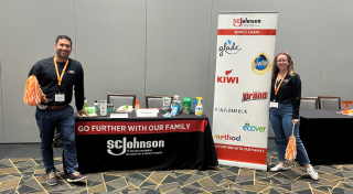 Two SCJ team members standing on either side of an SCJ table display at a recruiting event