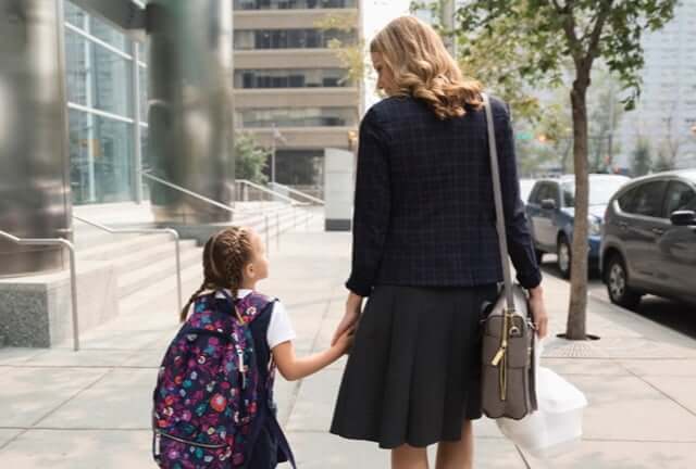 Mother and daughter walking on sidewalk
