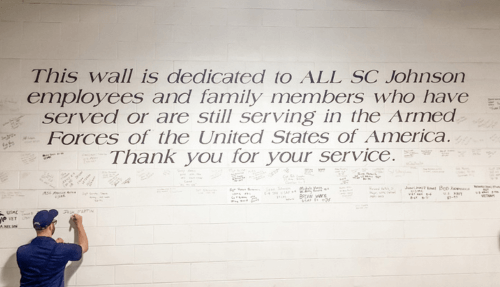 A wall with a message: This wall is dedicated to all SC Johnson employees and family members who have served or are still serving in the Armed Forced of the United States of America. Thank you for your service.