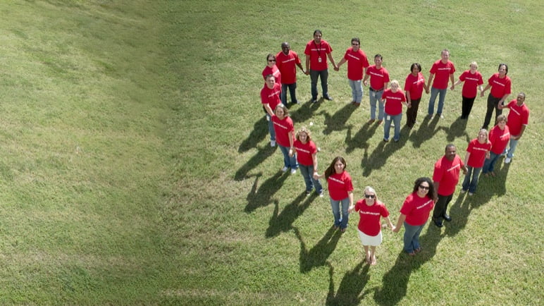 Group of people in red t-shirts standing in a heart formation