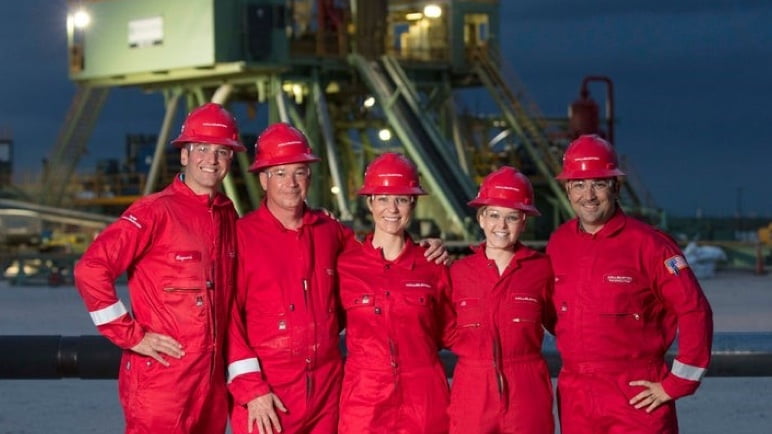 Group of people wearing red hard hats and red coveralls