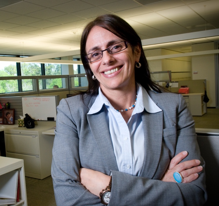 Woman with grey suit on and wearing glasses with her arms folded