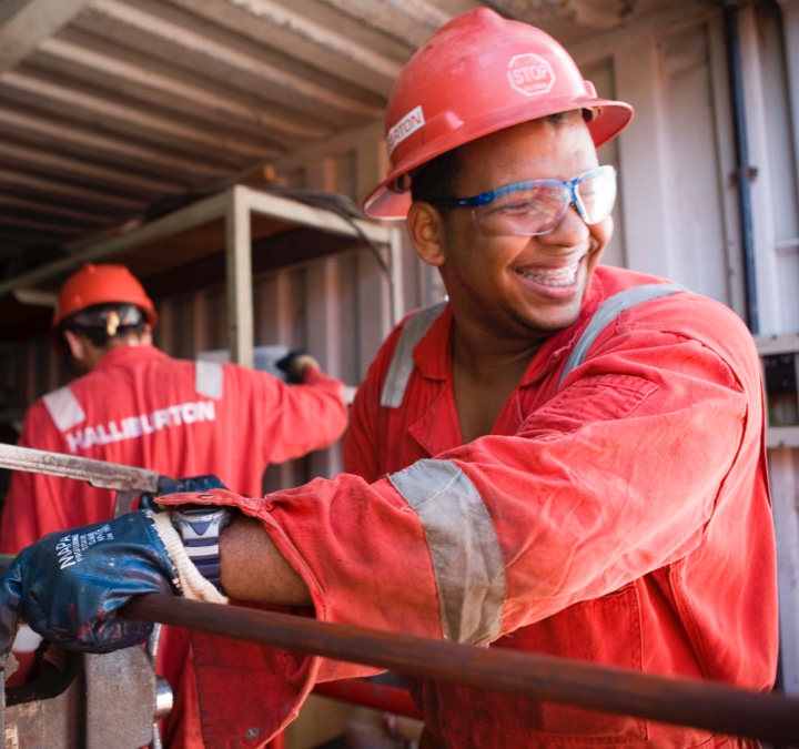 Man with red hard hat and protective glasses smiling