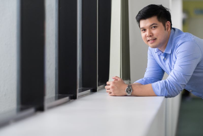 Malaysian Employee leaning against office window