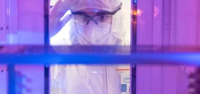 Scientist is protective equipment peering into machince