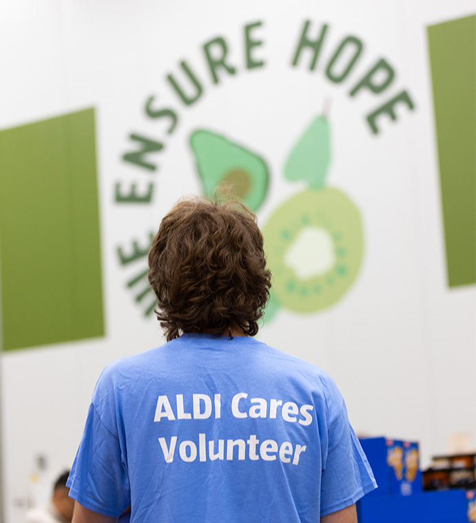 Volunteer helping outside while wearing an "Aldi Cares Volunteer" t-shirt