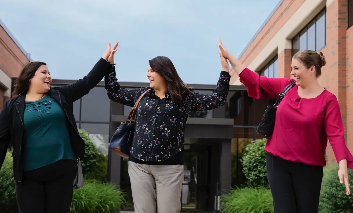 three women employees giving each other high five