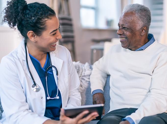 doctor and patient smiling while holding digital device