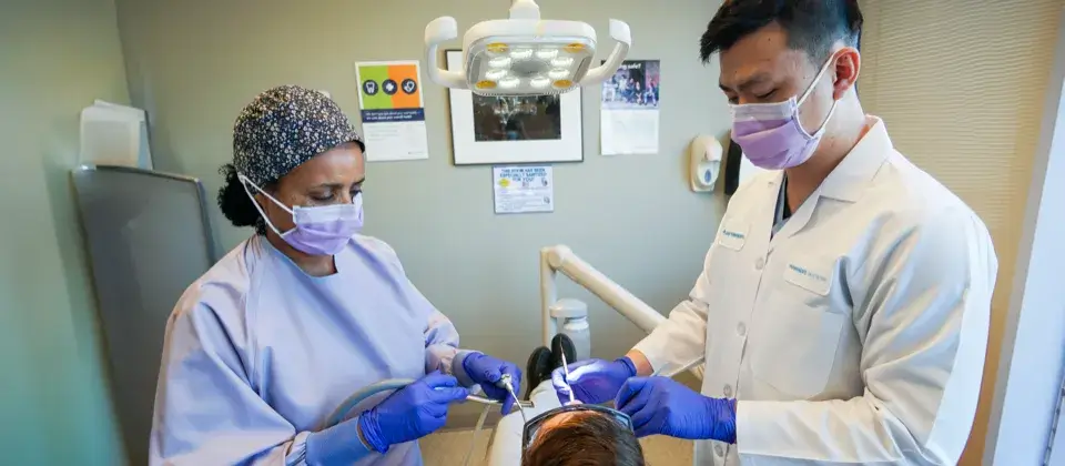 male dentist and female dental assistant performing a dental procedure on a patient