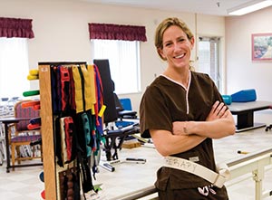 Smiling physical therapist with a large selection of tension bands in their exercise room