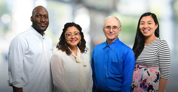Group of four smiling diverse employees in a work environment.
