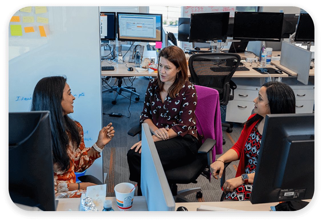 Female colleagues having a conversation around their desks