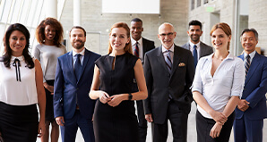 A group of professionally dressed men and women standing together and smiling