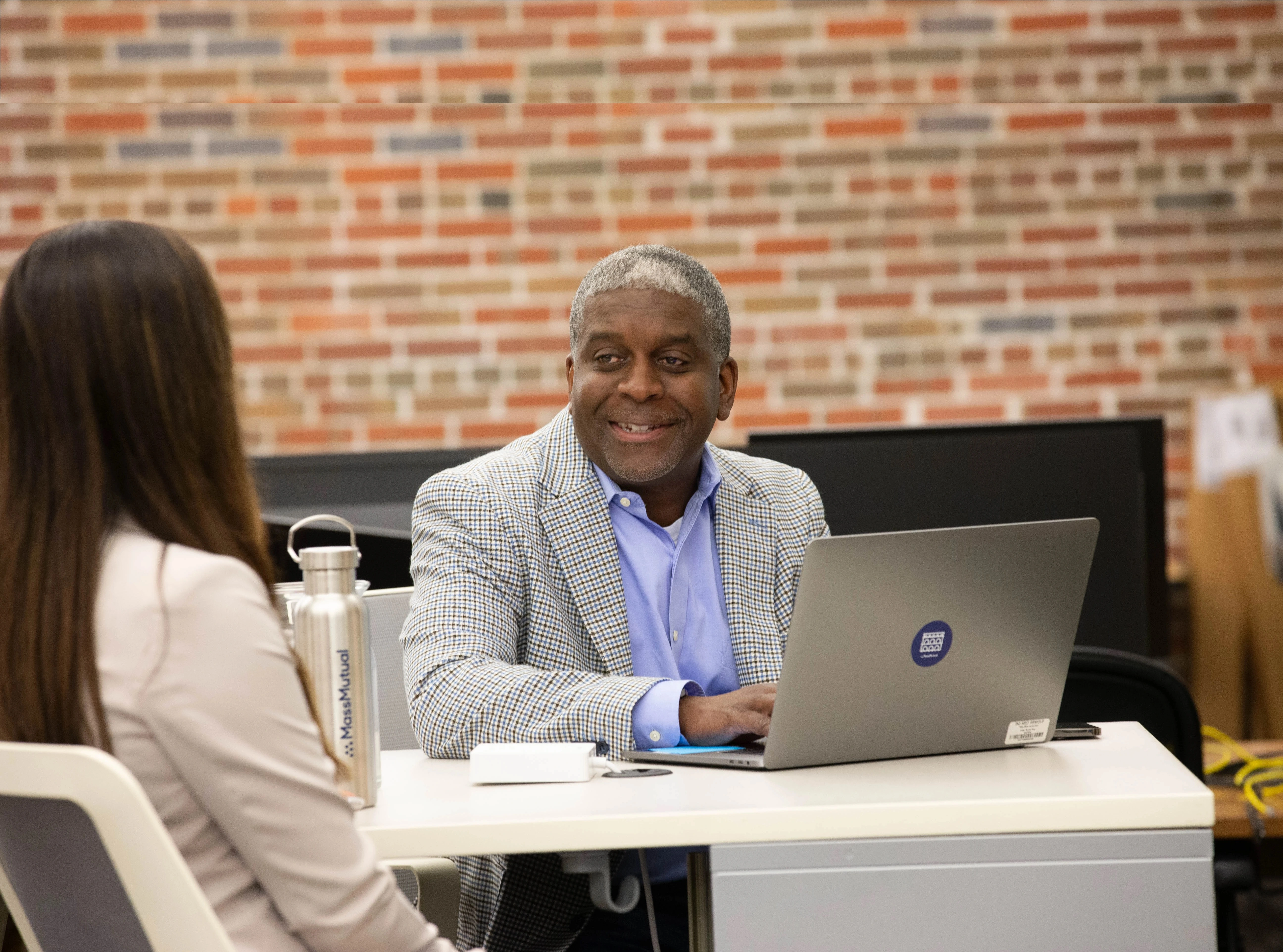 Two people smiling while standing at a computer