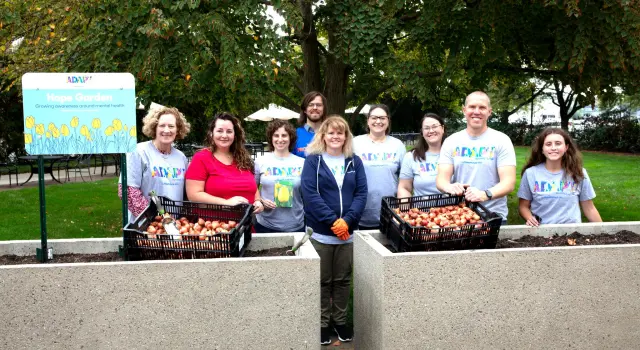 large group smiling and holding a Hope Garden sign