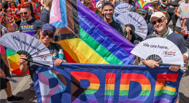 people smiling at the camera while walking in a parade