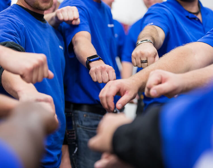 People in blue McKesson shirts with their hands extended in the middle of a group huddle