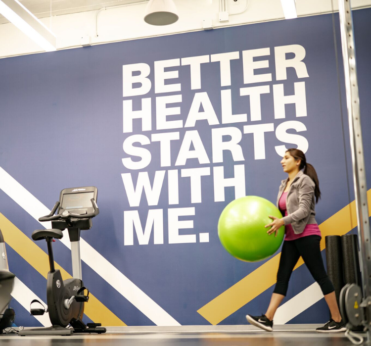 Woman in gym carrying a workout ball