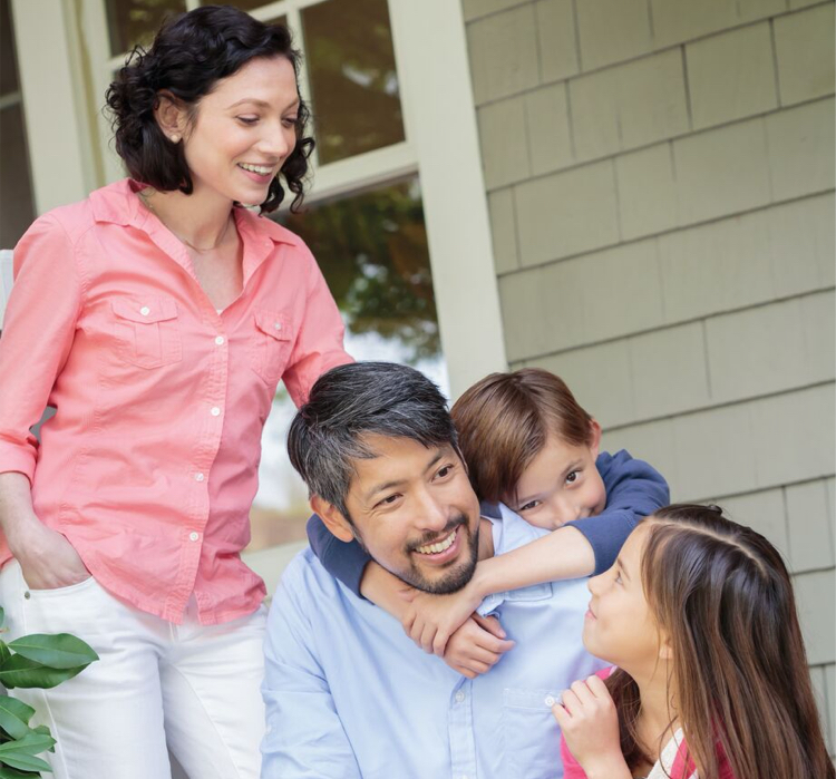 Parents with two children hugging and smiling outside