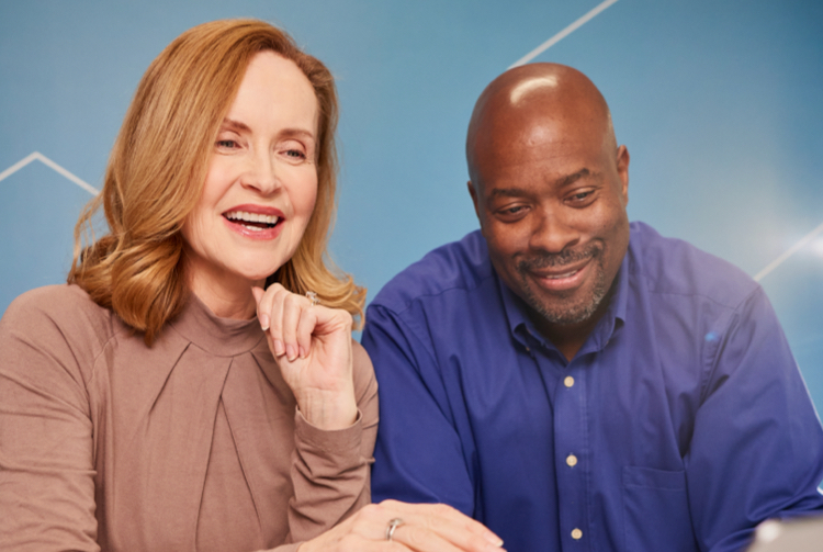 Man and woman smiling while looking at laptop