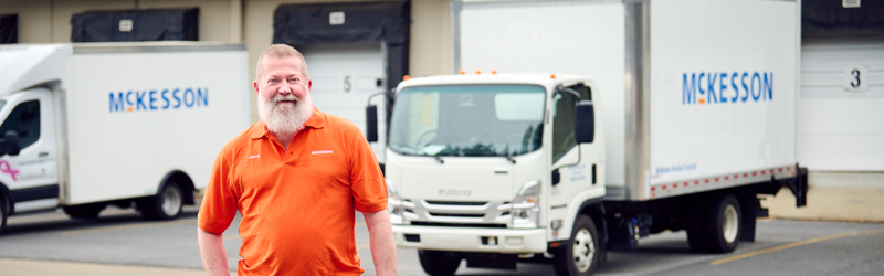 Man in bright shirt standing in front of two trucks