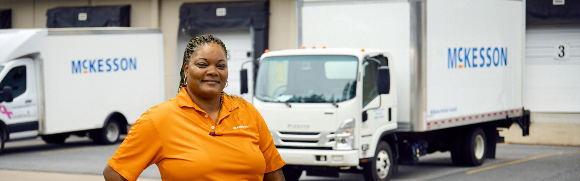 Woman in bright shirt standing in front of two trucks