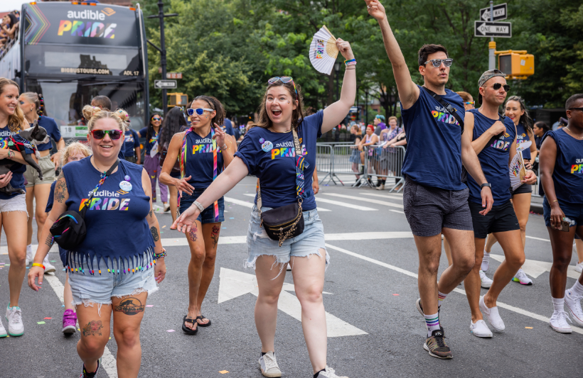 Colleagues smiling next to one another while marching in a parade.