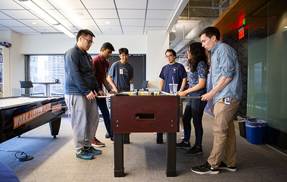 Group of people playing at a foosball table