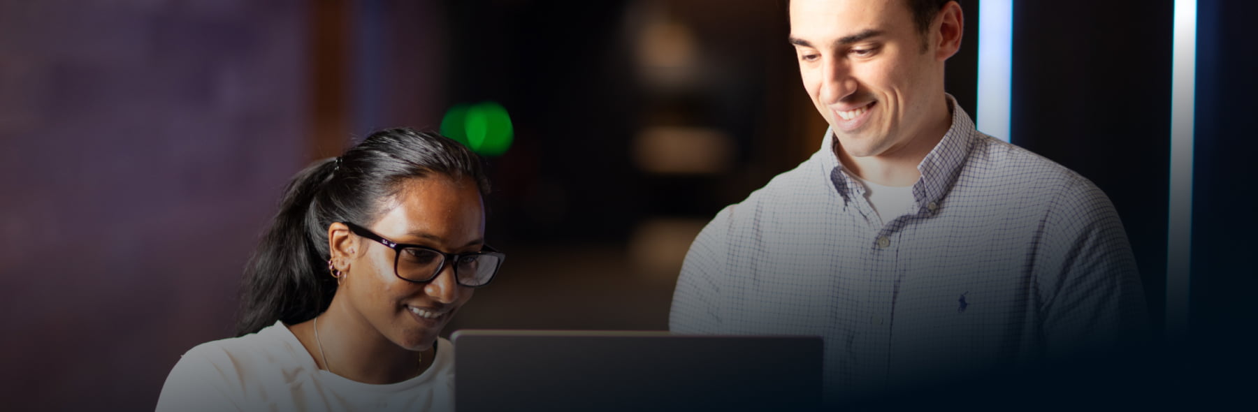 Male and female colleagues looking at the same laptop screen