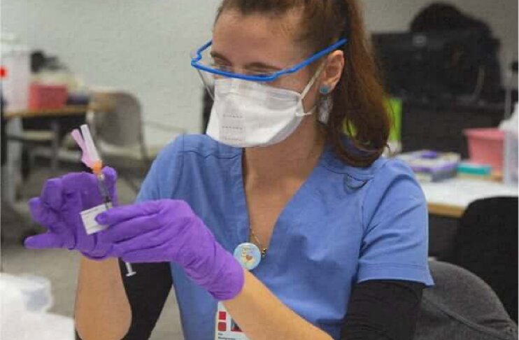 Woman in vaccine clinic preparing to administer vaccine