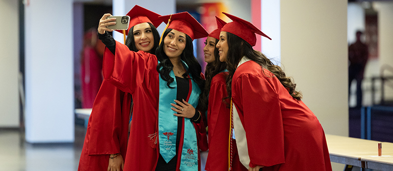 UNM graduates pose in a group for a selfie