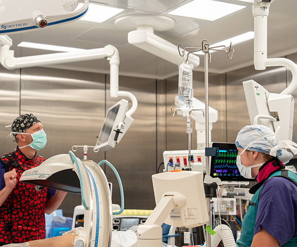 Trauma surgeon Dr. Matthew W. and X-ray Tech Marjorie work together preparing for surgery in the operating room