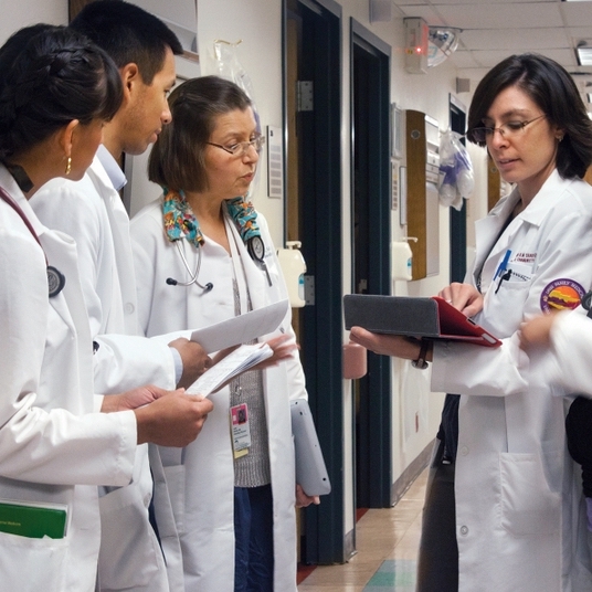 four people in white labcoats checking charts