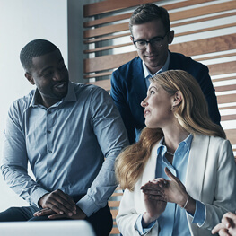two men and a woman in business attire, conversing together inside an office