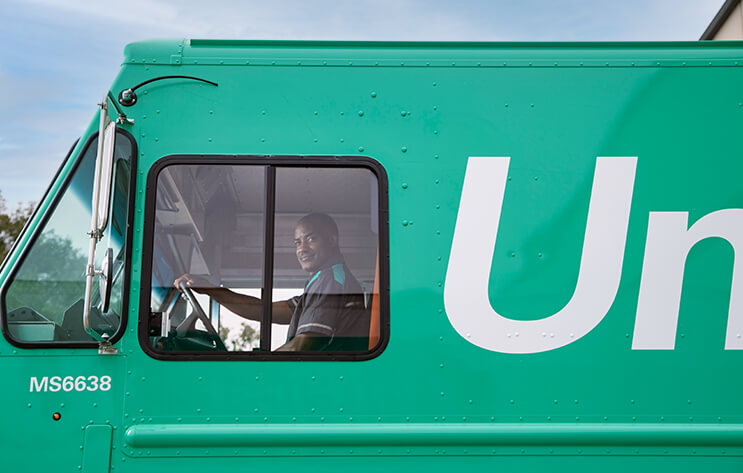 A man sitting in a green UniFirst truck.