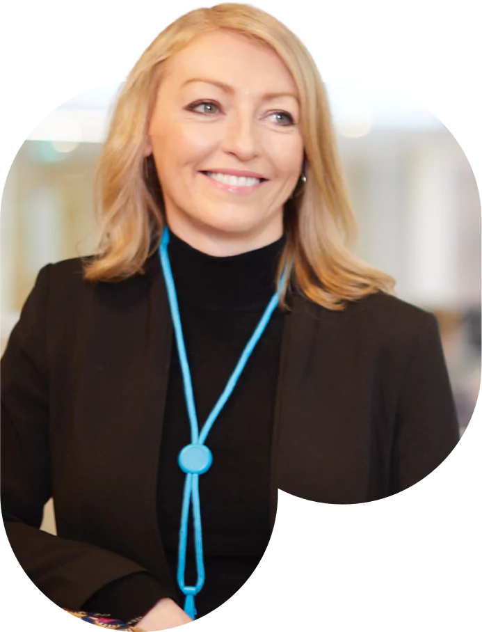 A professional woman in a suit and tie smiling confidently at the camera.