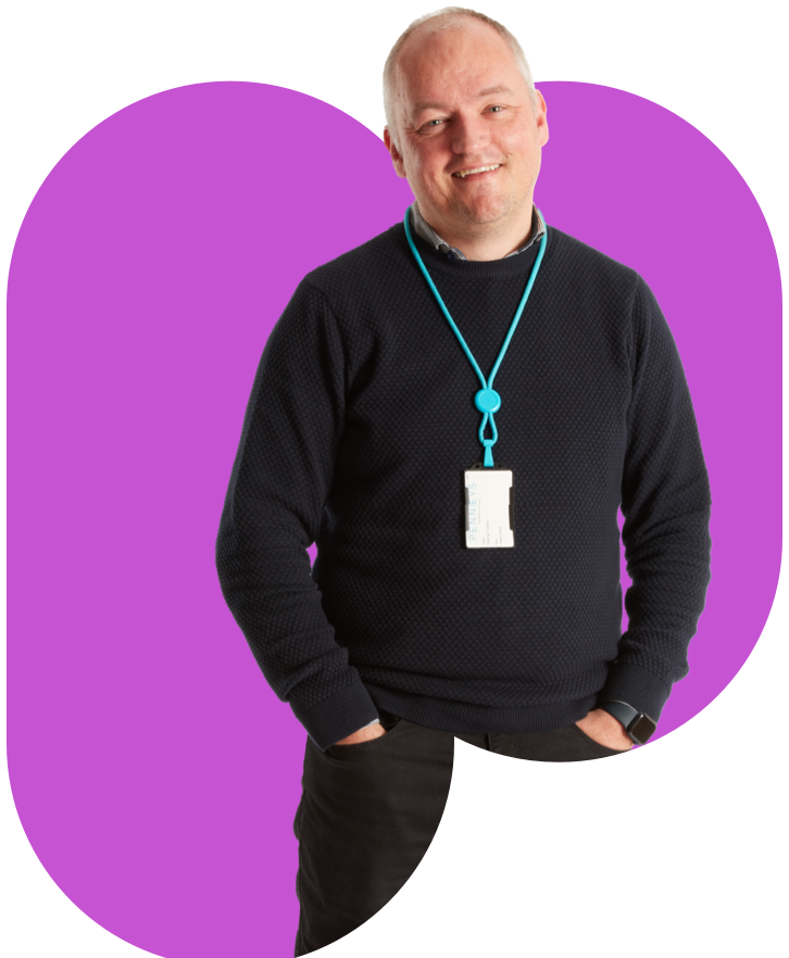 A man wearing a black sweater against a purple background.