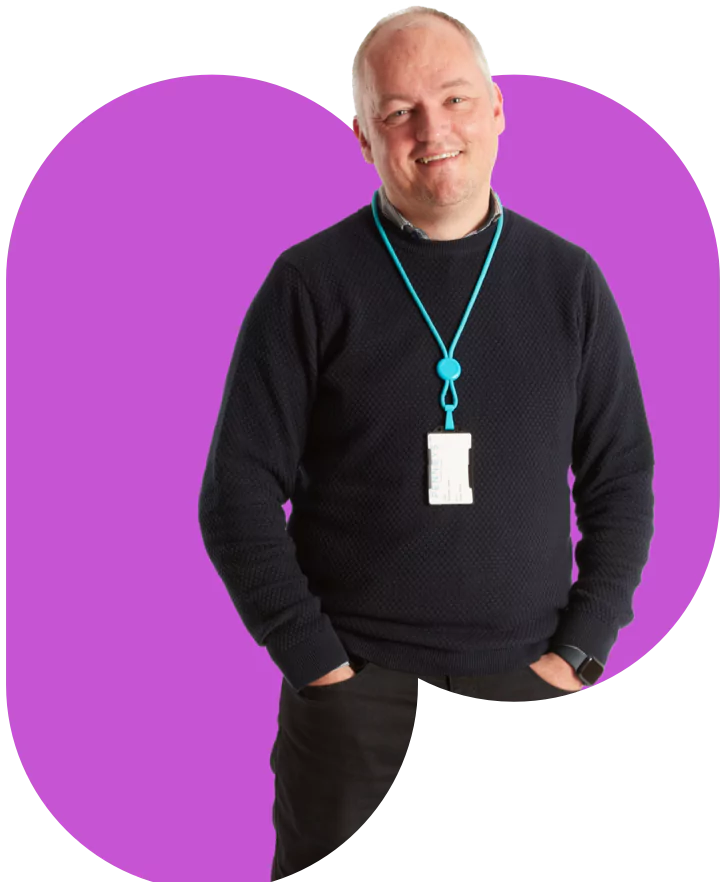 A man wearing a black sweater against a purple background.