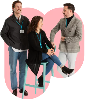 Three people on a chair with pink background.