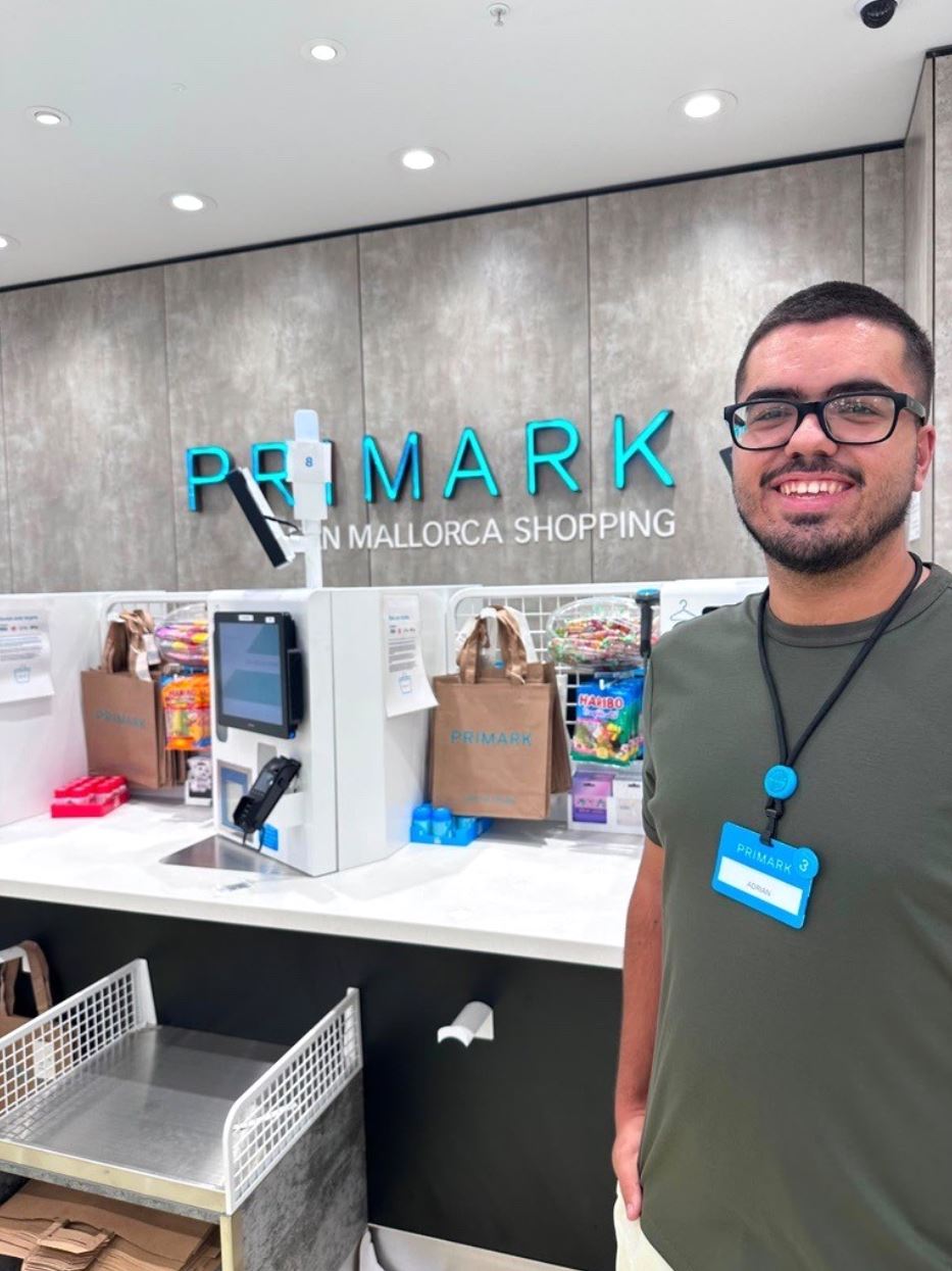 Male colleague standing in a Primark store with hands in pockets and smiling