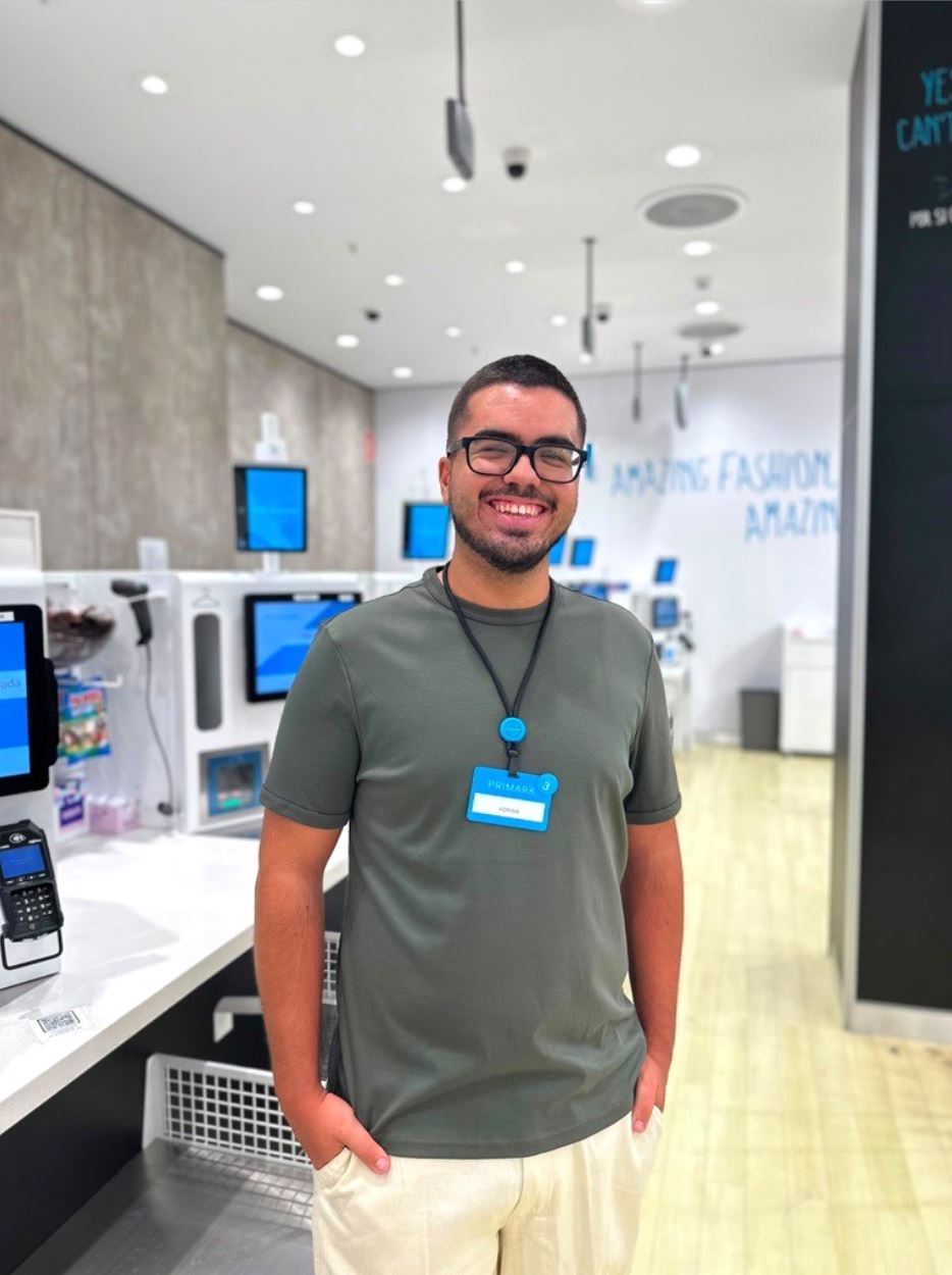 Male colleagues standing in Primark store near tills with hands in pockets