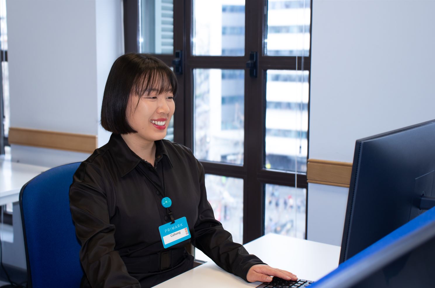 Female colleague smiling and working at a desk in a Primark office