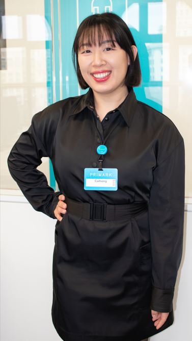 Female colleague smiling with hand on hip in a Primark office