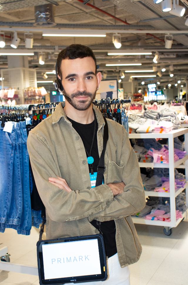 Male colleague standing in a Primark store with arms crossed and tablet on shoulder