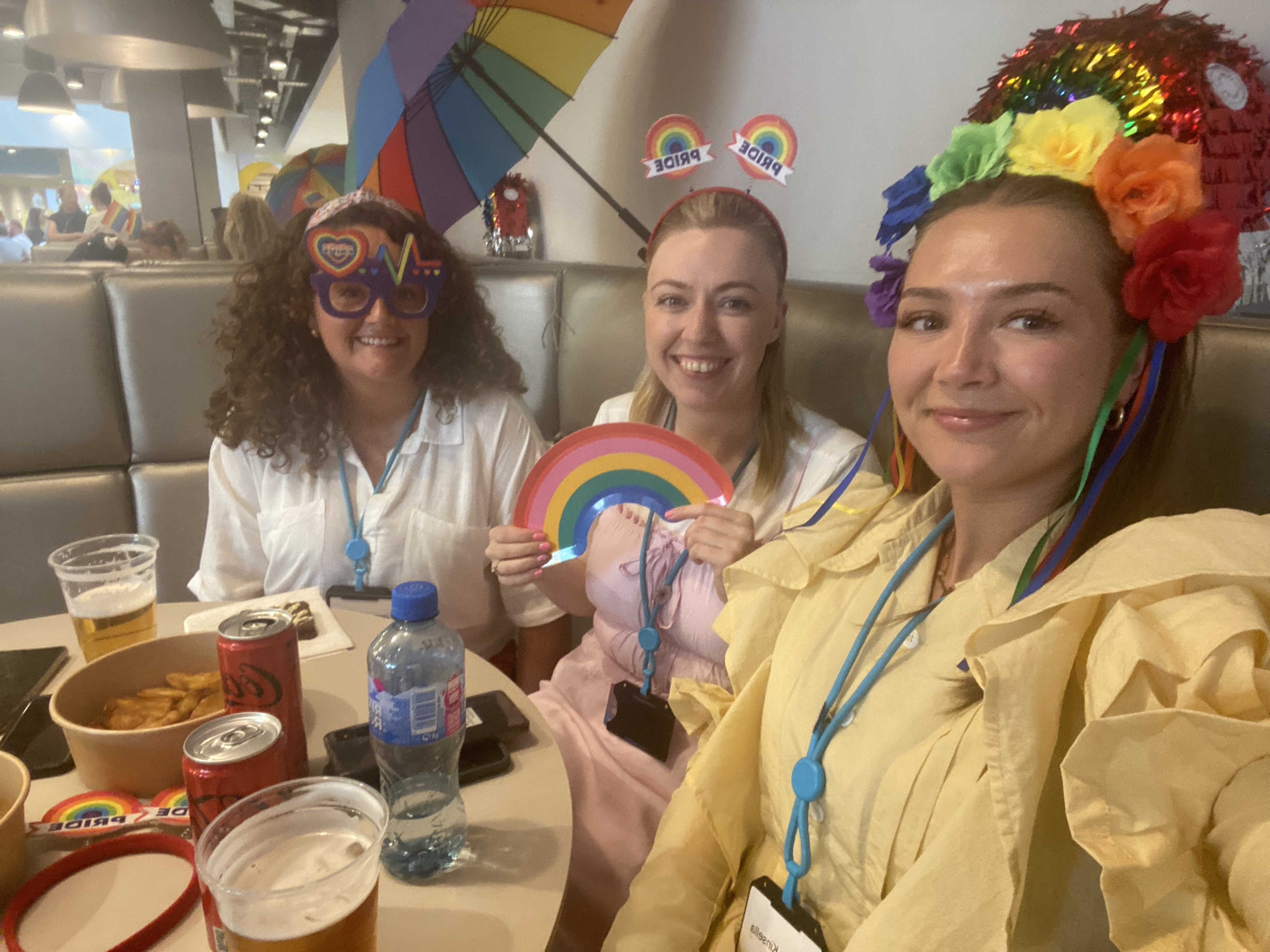 Three female colleagues smiling and celebrating Pride in a Primark office