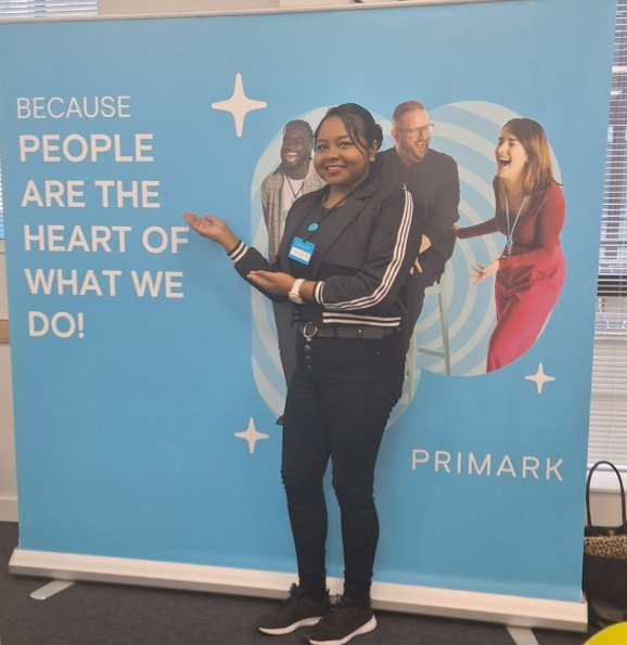 Colleague smiling and posing at a Primark pull-up banner