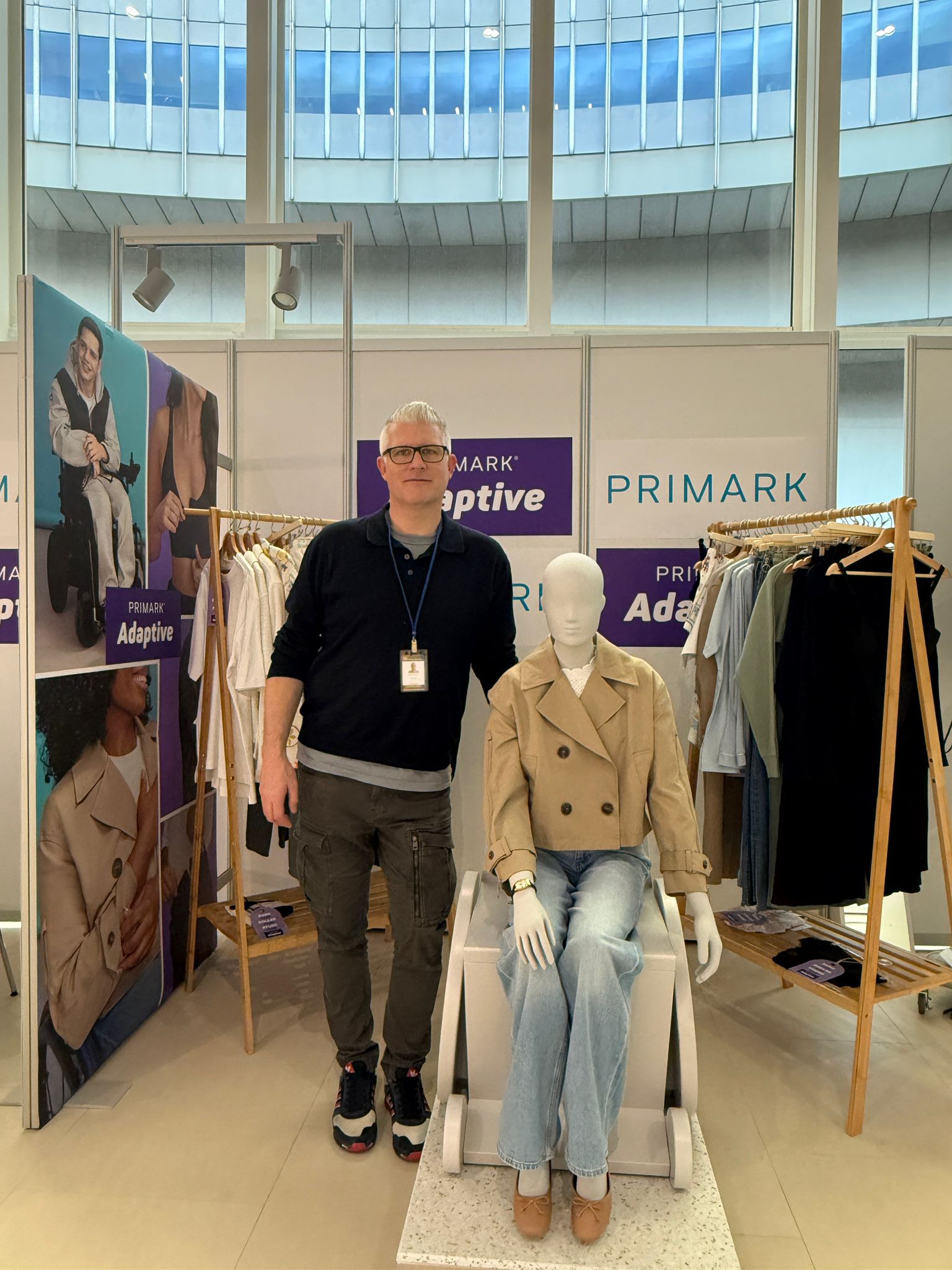 Male colleague standing beside a mannequin wheelchair at a Primark Adaptive stand at a convention