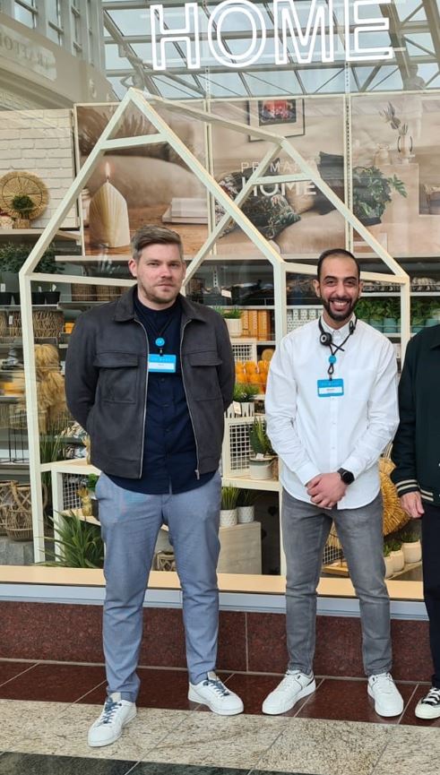 Two male colleague standing together and smiling outside a Primark store
