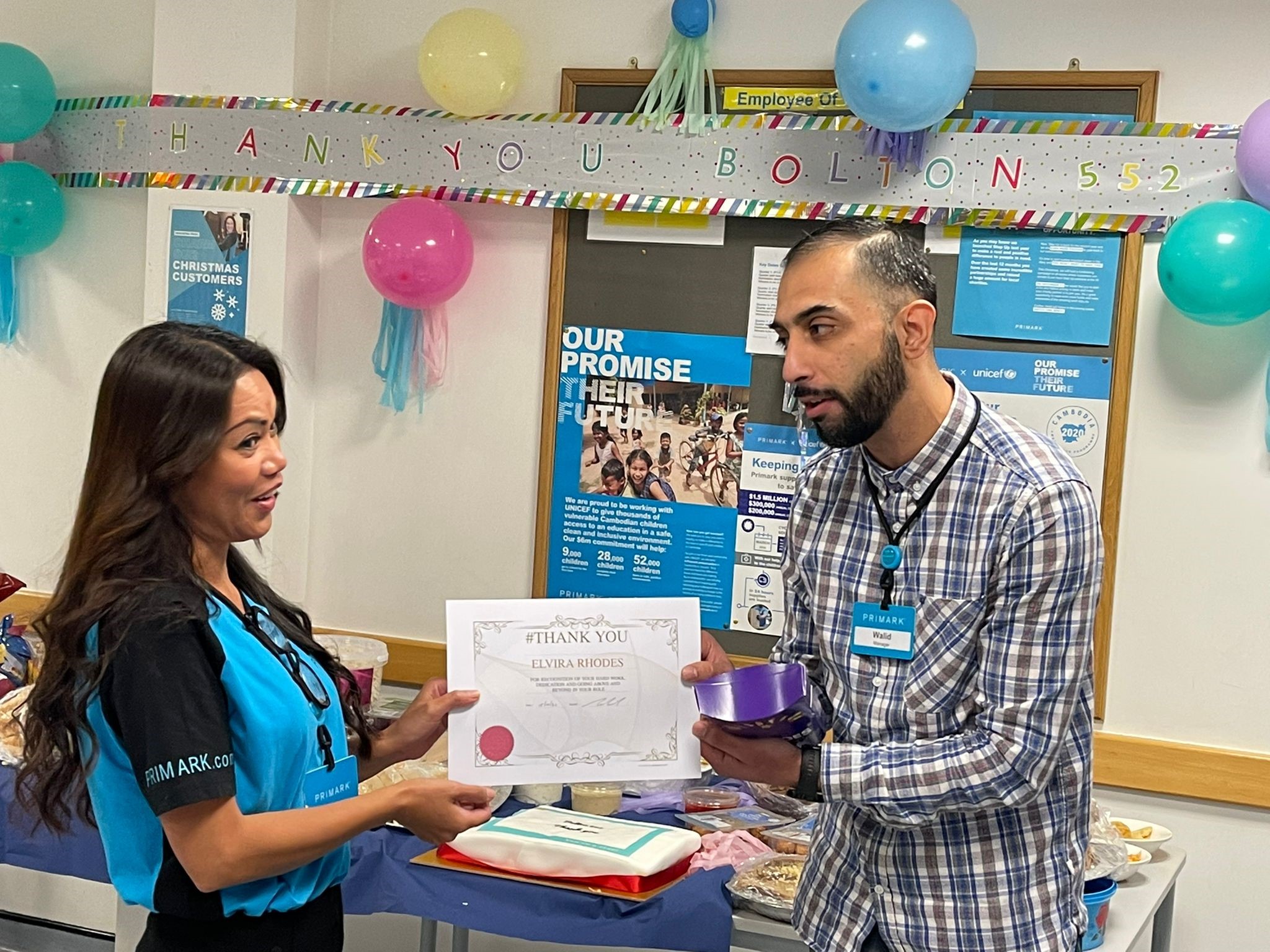 Male colleague giving an award certificate to a female colleague in a Primark store office