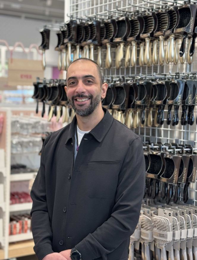 Male colleague smiling with hands together in a Primark store